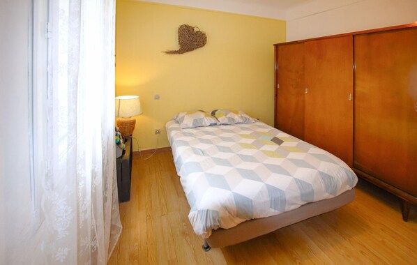 Une chambre à coucher avec un lit, une armoire en bois, une lampe et un élément de décoration murale.