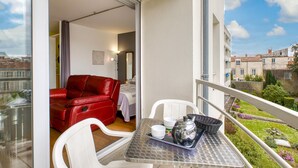 A balcony with a table set for two, a red leather sofa, and a view of the cityscape. - Magnifique app à la Rochelle (La Rochelle)