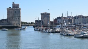 A marina with boats docked, a castle, and buildings in the background. - Magnifique app à la Rochelle (La Rochelle)