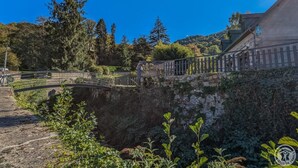 A stone bridge over a river, surrounded by greenery and trees.