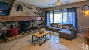 A cozy living room with a stone fireplace, a sofa, a coffee table, and a ceiling fan.