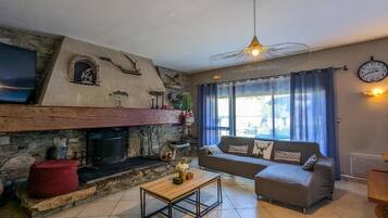 Un salon chaleureux avec une cheminée en pierre, un canapé, une table basse et un ventilateur de plafond.