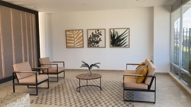 Uma sala de estar moderna com piso xadrez, dois sofás, uma mesa de centro e três obras de arte emolduradas na parede.