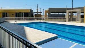 Piscina com deck revestido em azulejo e guarda-corpo metálico.