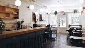 A cafe with a wooden counter, bar stools, tables, and hanging lights. - Historic Uptown 2BD w/Shared Patio Pet-friendly (St. Petersburg)