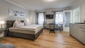 Een moderne hotelkamer met een bed, nachtkastje en een zithoek met stoelen en een tafel.