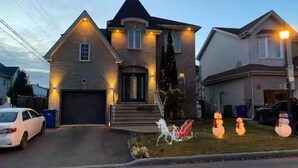 A two-story house with a garage, a driveway, and a lawn with a snowman decoration.