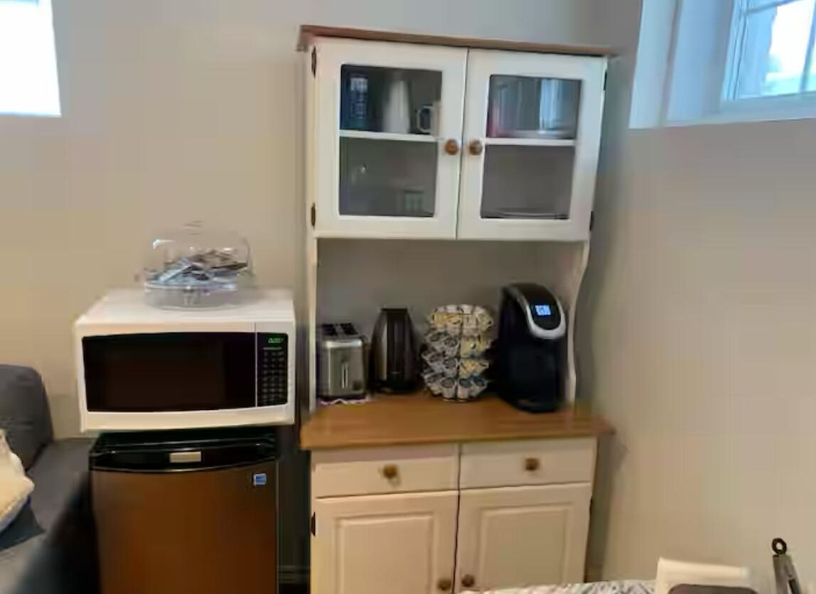 A compact kitchenette with a microwave, toaster, and coffee maker on the countertop.