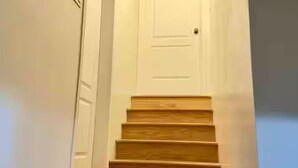 A wooden staircase leading to a white door.