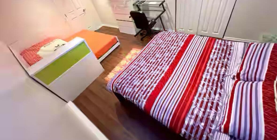 A bedroom with a bed, a desk, and a chair.