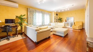Ein modernes Wohnzimmer mit einer Couch, einem Hocker und einem Schreibtisch mit einem Computer.