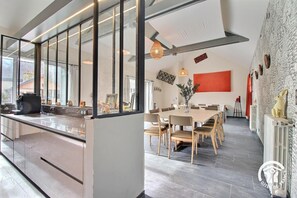 Una cocina moderna con una isla grande, un comedor con una mesa larga y una sala de estar con chimenea.