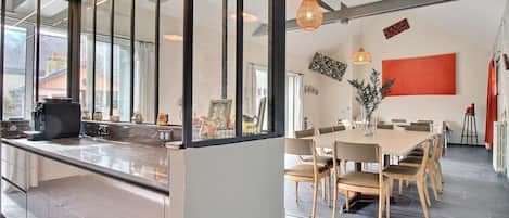 A modern kitchen with a large island, a dining area with a long table, and a living space with a fireplace.