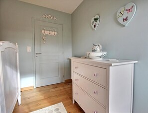 Una habitación con una puerta blanca, un aparador con cajones y platos decorativos de mariposas en la pared.
