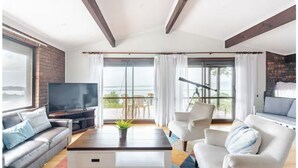 A modern living room with a sofa, armchairs, a coffee table, and a TV. - Entire spectacular lake and ocean view holiday house (Lake Heights)