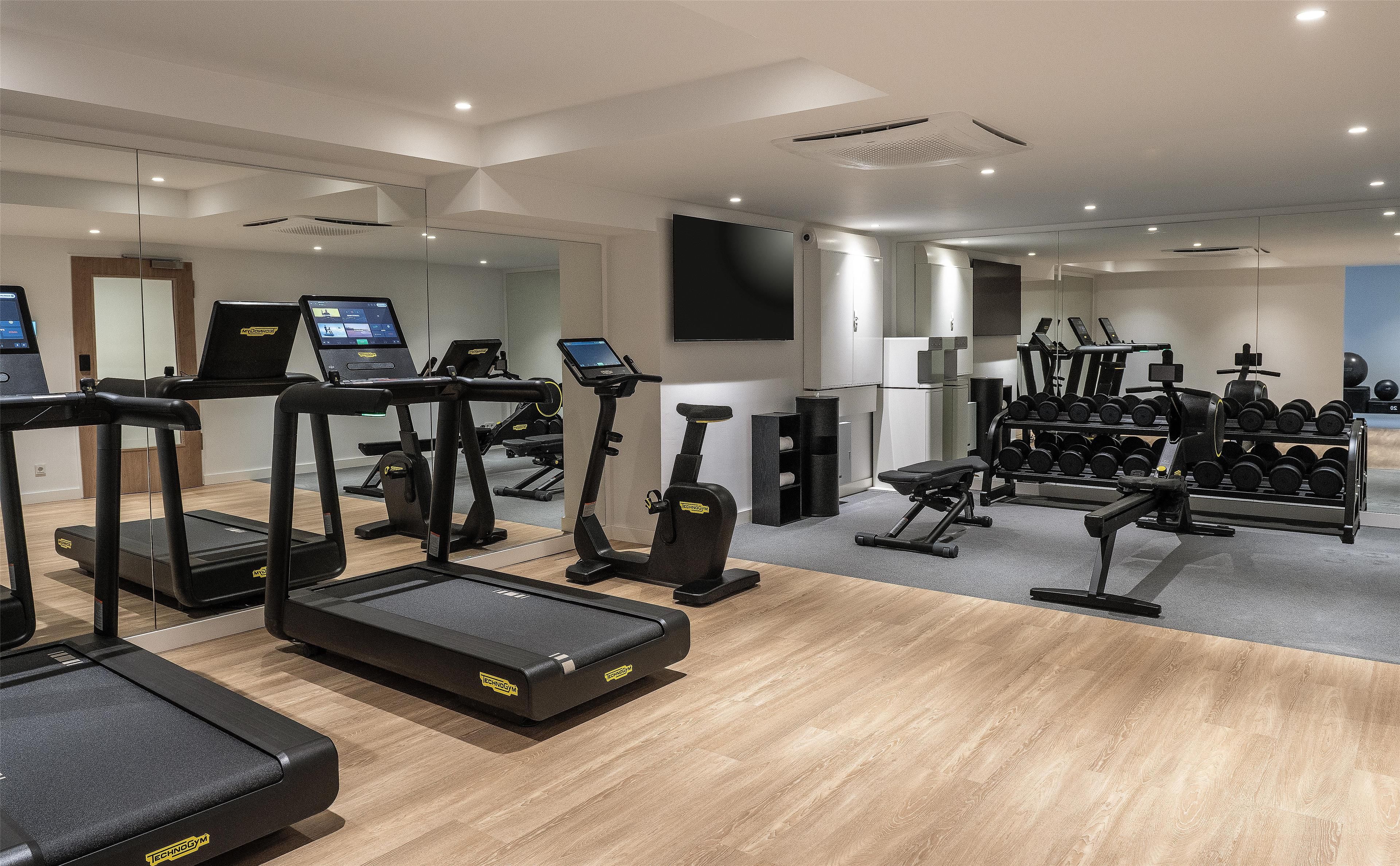 A gym with treadmills, exercise bikes, and a weight rack.