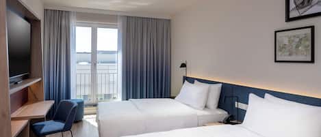 A hotel room with two beds, a desk, a chair, a TV, and a balcony with curtains.