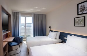 A hotel room with two beds, a desk, a chair, a TV, and a balcony with curtains.