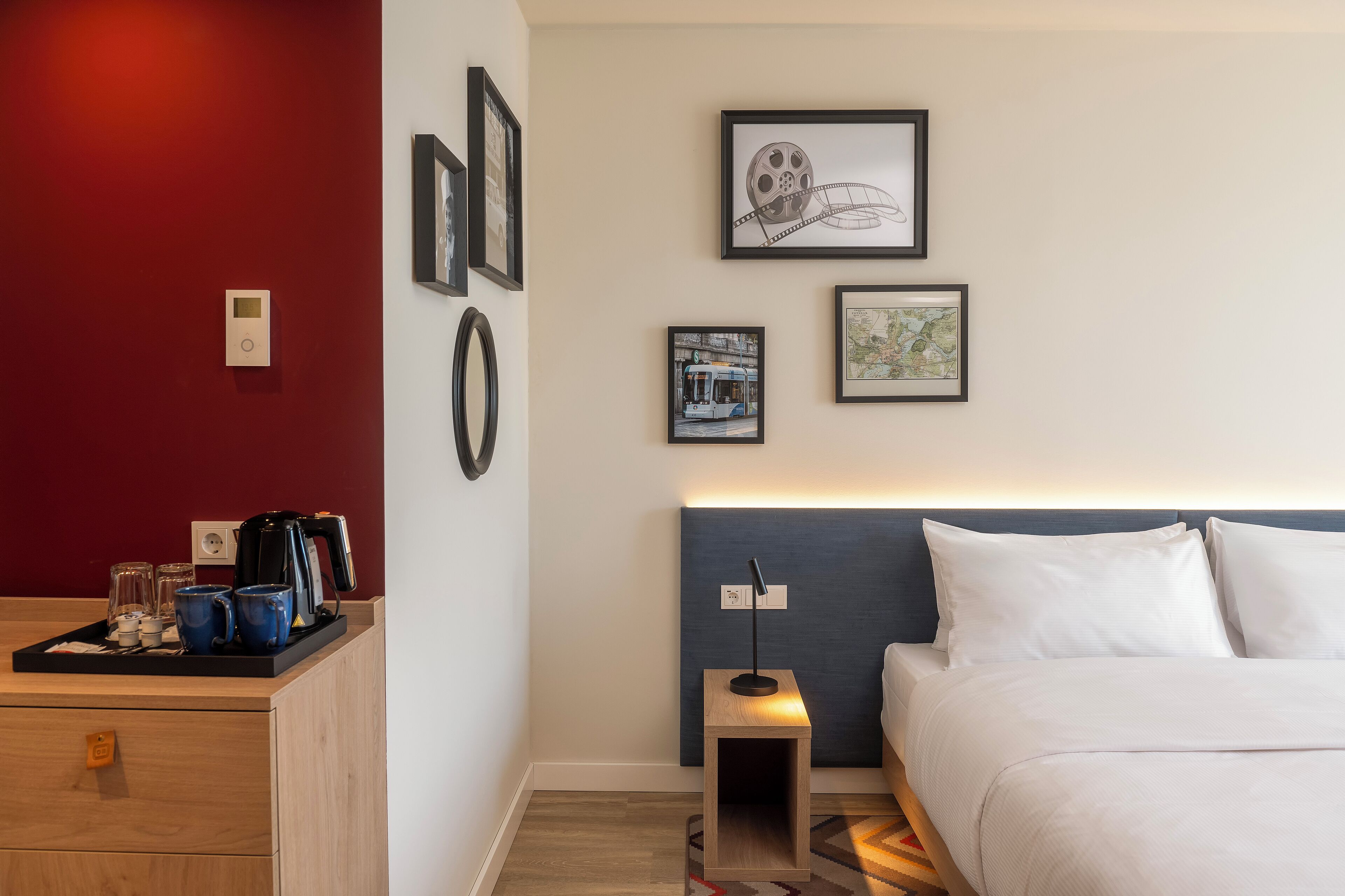 A hotel room with a bed, bedside table, and a wall-mounted coffee machine.