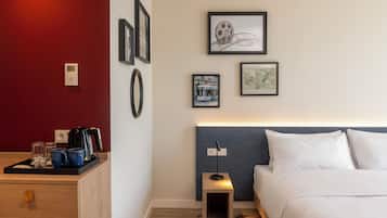 A hotel room with a bed, bedside table, and a wall-mounted coffee machine.