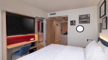 A hotel room with a bed, a TV, a desk, and a chair.