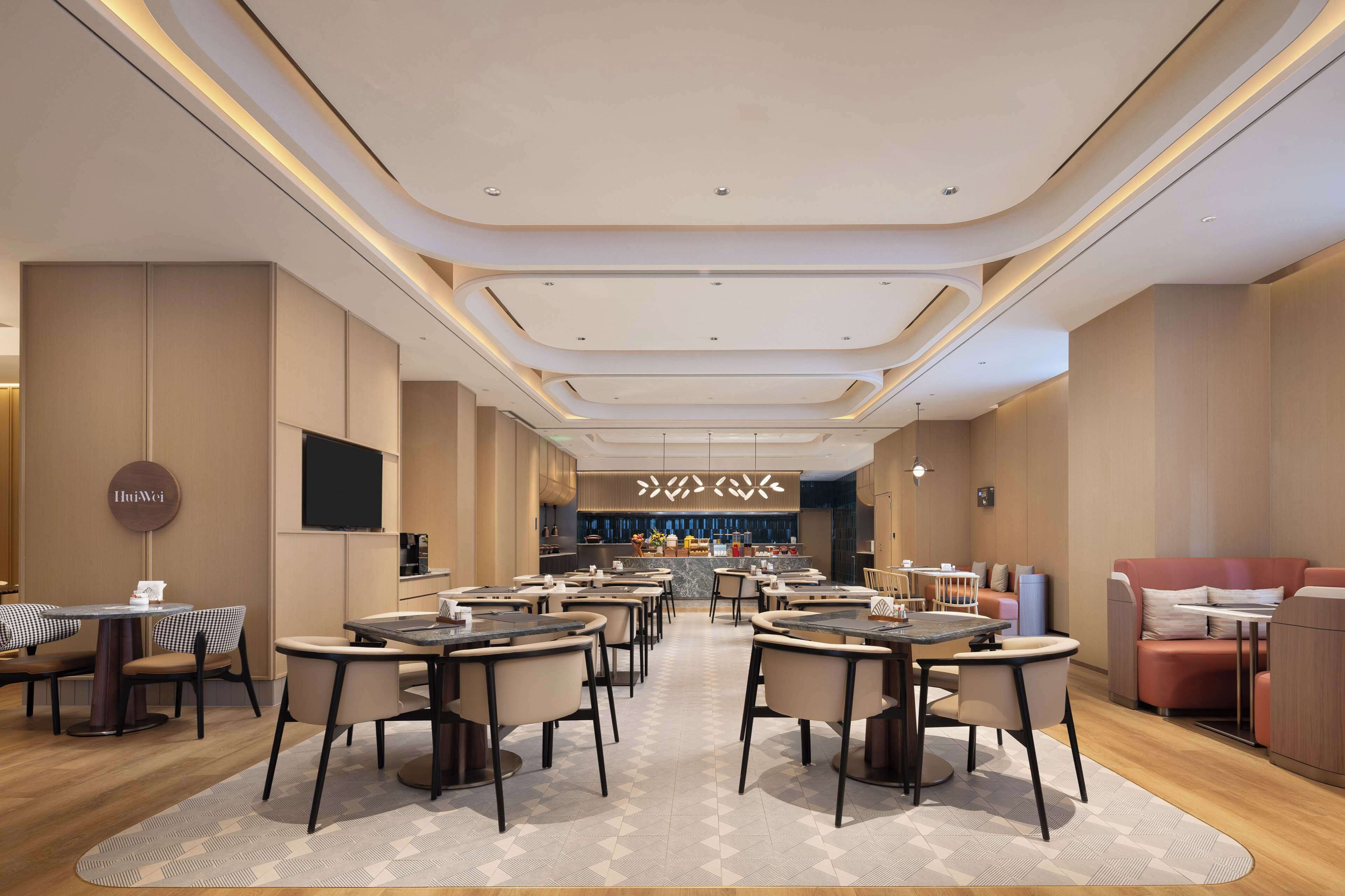 A modern restaurant with round tables and chairs, a bar area, and a seating area with sofas.