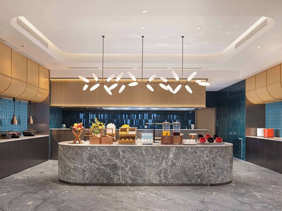 A modern lobby with a marble reception desk, pendant lighting, and a blue-tiled wall.