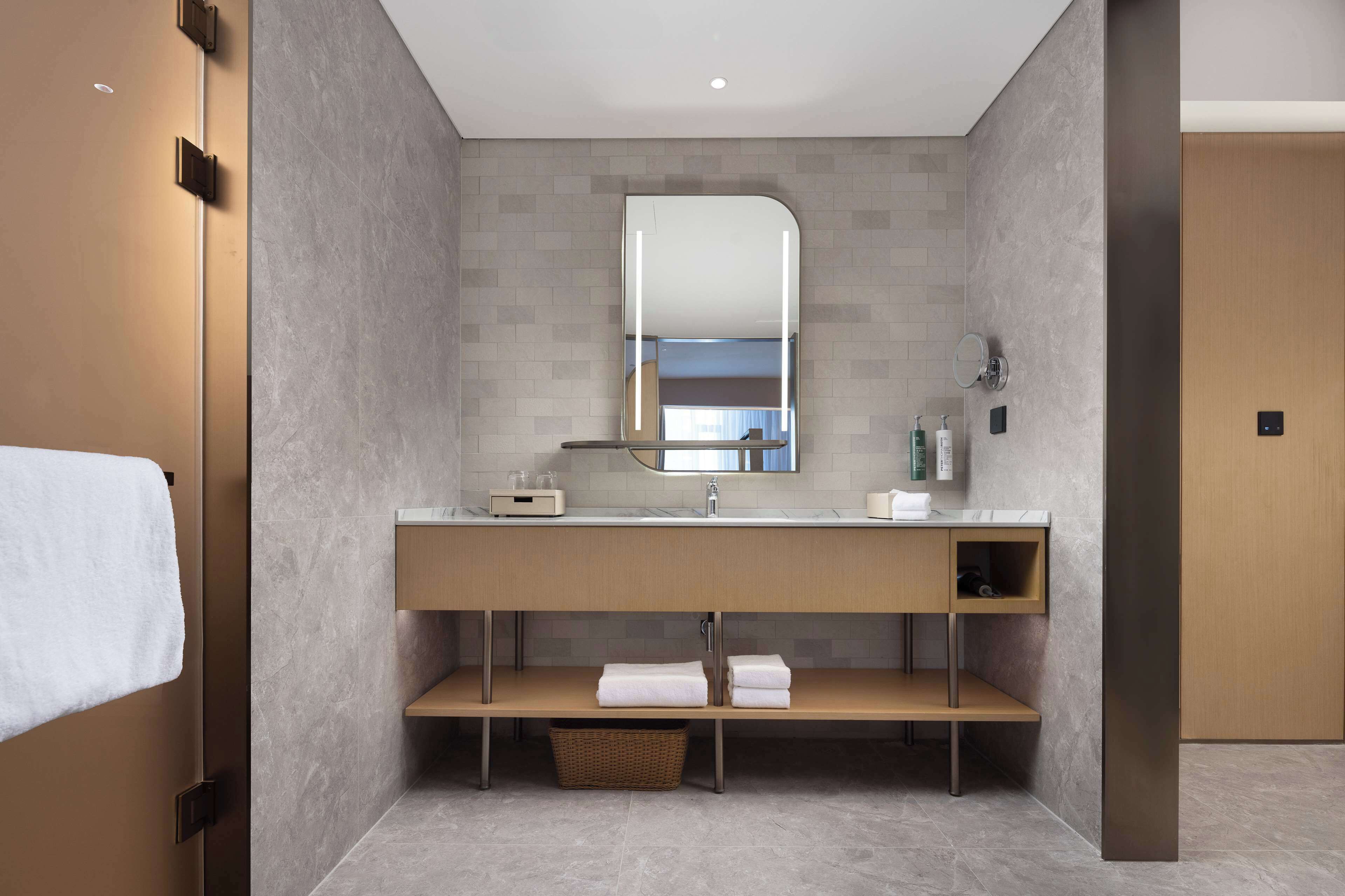 A modern bathroom with a large mirror, a sink, and a wooden vanity.