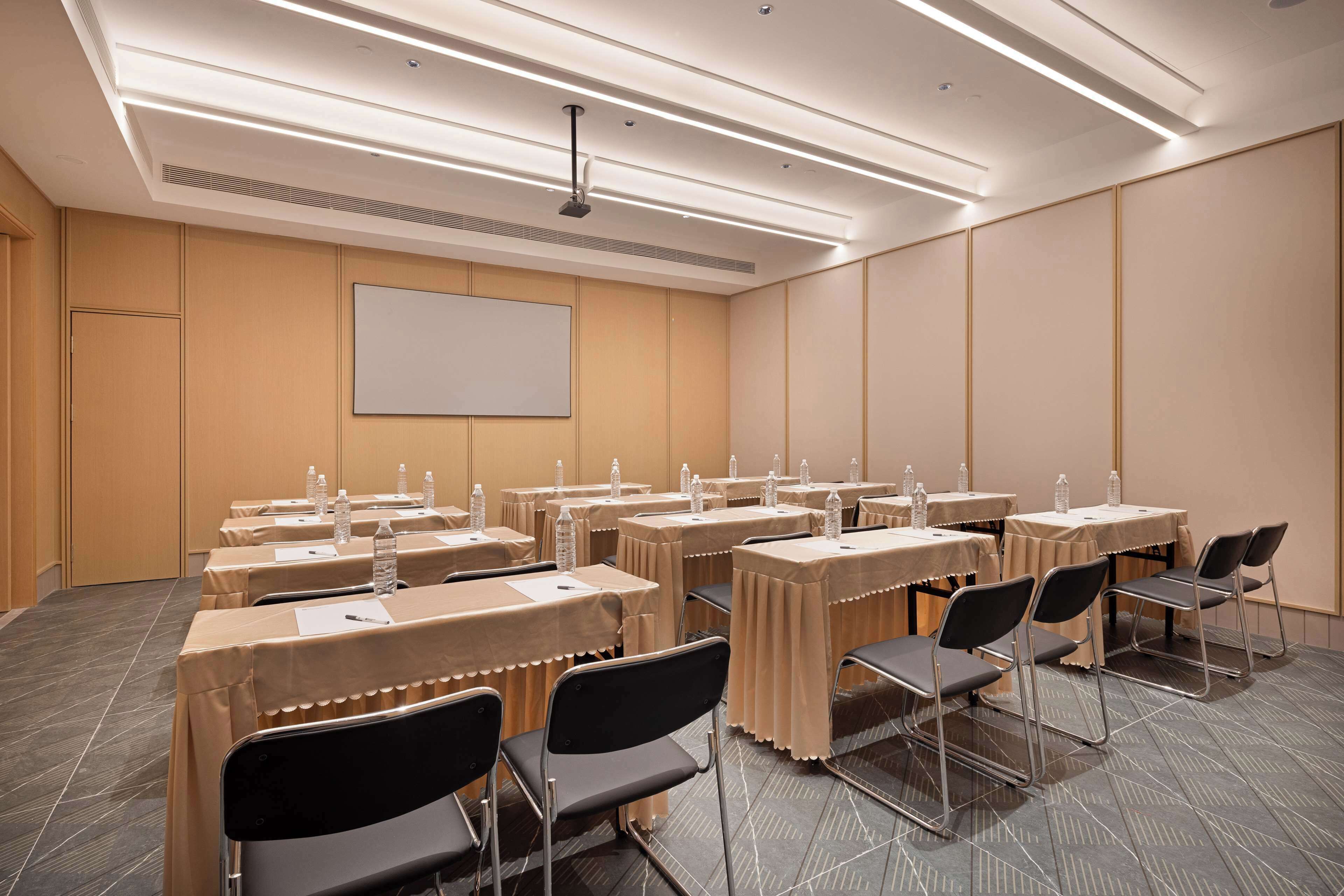 Une salle de conférence équipée de tables, de chaises et d’un écran de projection.