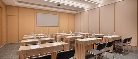 Une salle de conférence équipée de tables, de chaises et d’un écran de projection.
