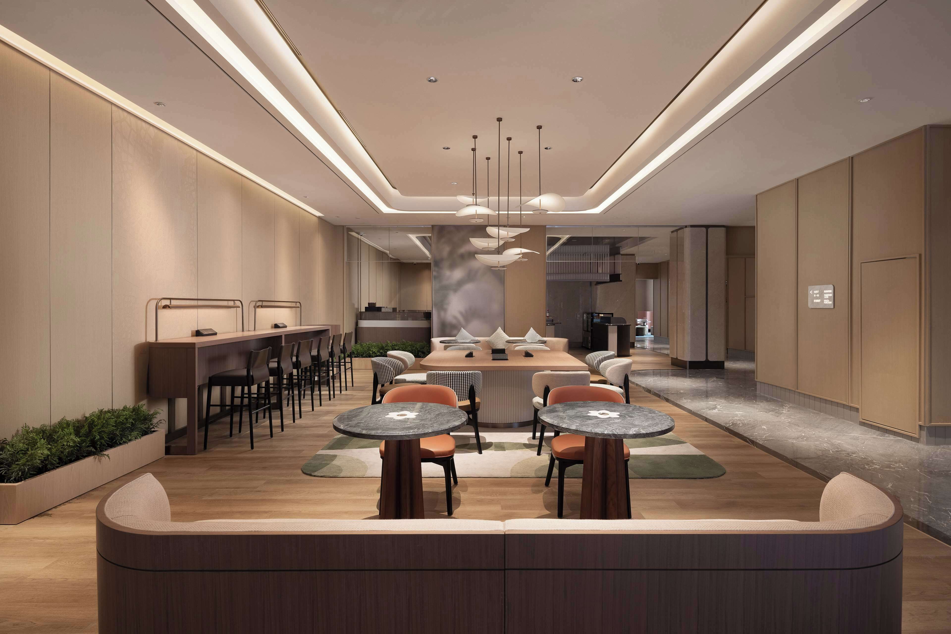 A modern hotel lobby with a central seating area, a reception desk, and a large decorative sculpture.