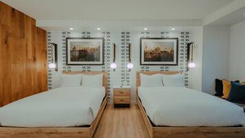 A double room with two beds, wooden headboards, white bedding, and two framed pictures on the wall.