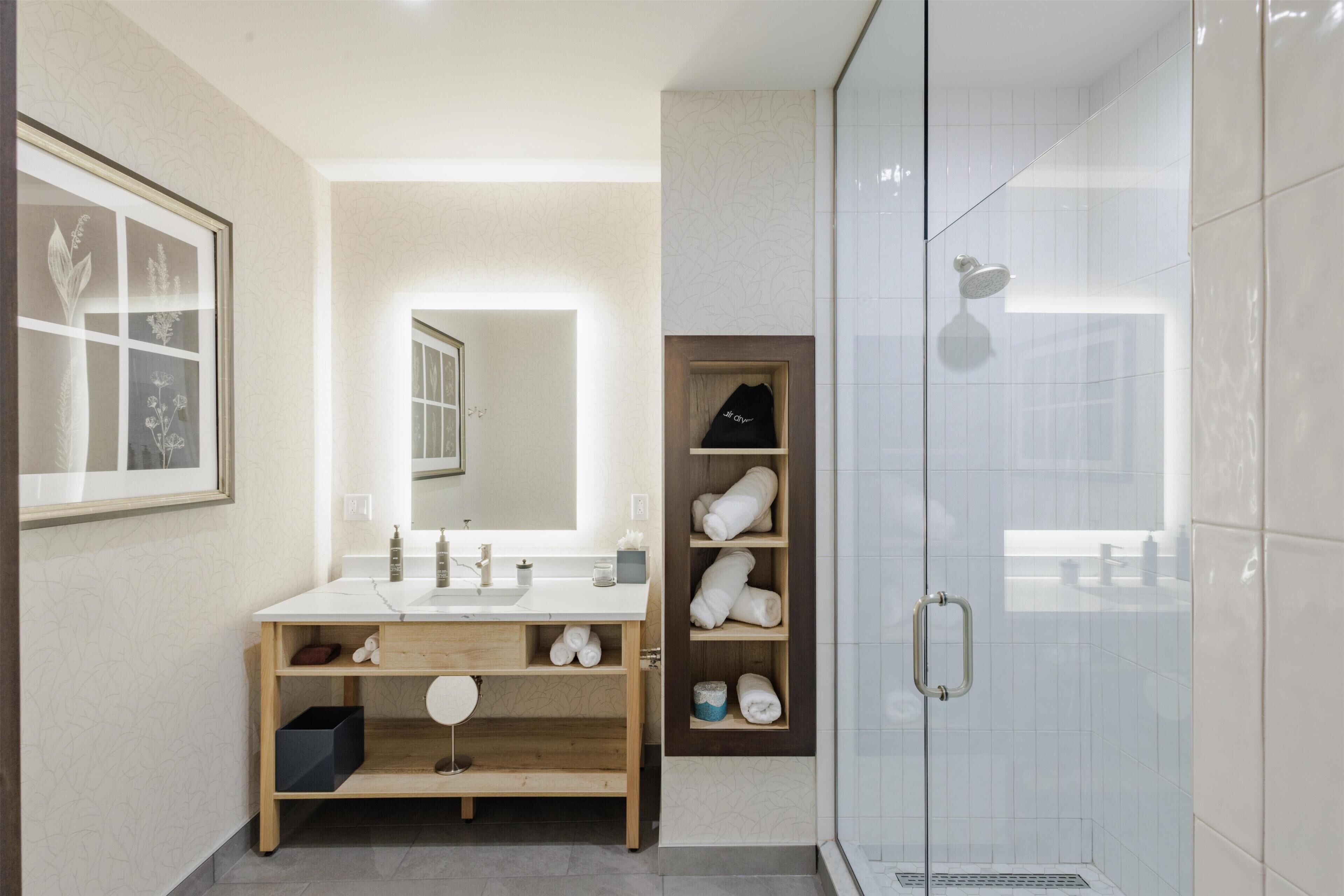 Uma casa de banho moderna com lavatório, espelho e chuveiro.
