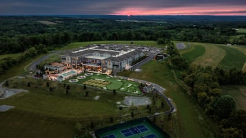 A large hotel complex with multiple buildings, a swimming pool, tennis courts, and landscaped gardens.