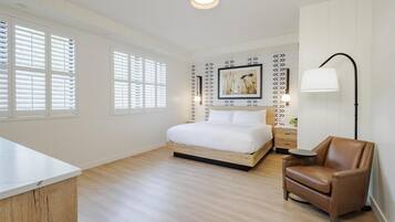 A bedroom with a bed, a chair, a bedside table, and a lamp.