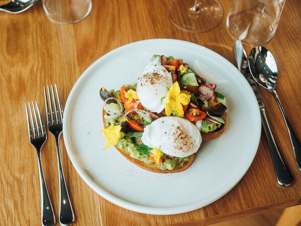 A plate of food with a poached egg, avocado, and vegetables on a white plate. - Skaneateles Fields Resort & Spa, Curio Collection By Hilton (Skaneateles)