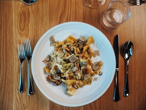 A plate of pasta with mushrooms and cheese on a wooden table. - Skaneateles Fields Resort & Spa, Curio Collection By Hilton (Skaneateles)