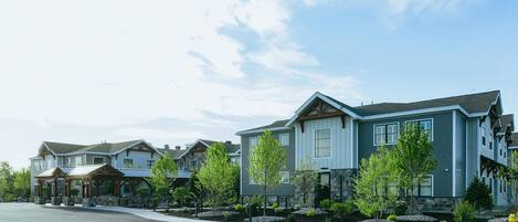 A residential area with modern houses, a covered walkway, and a well-maintained lawn.