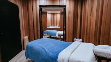 Une pièce comprenant un lit, une table de massage, un petit lavabo et un lambris en bois.