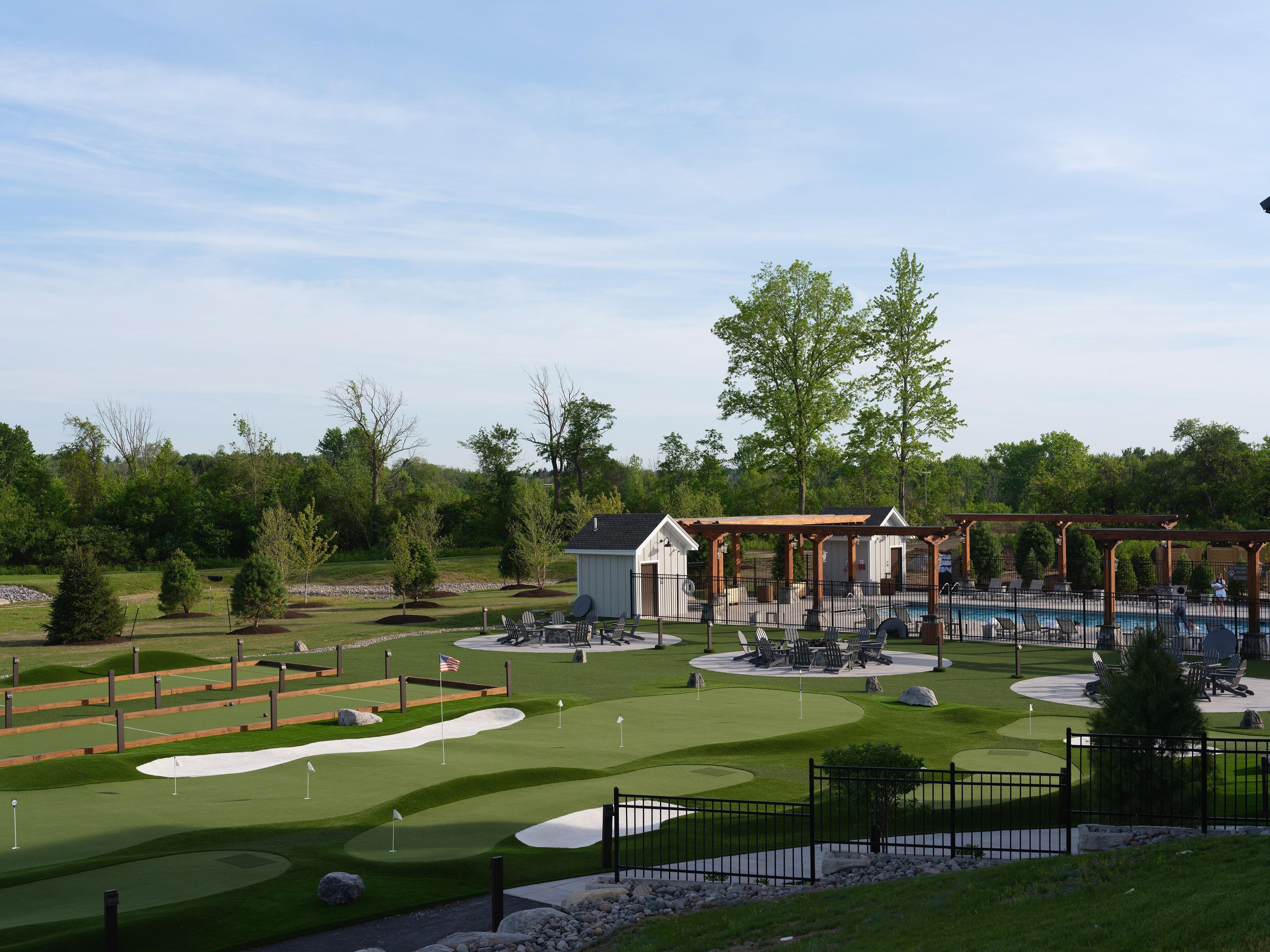 A golf course with a pool area, outdoor seating, and a small building.