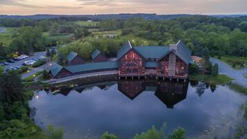 A lakeside lodge with a reflective water body, multiple buildings, and a parking area.