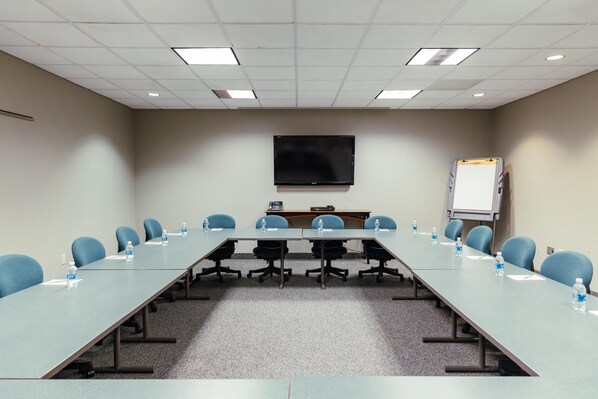 A conference room with a long table, chairs, a flat-screen TV, a whiteboard, and water bottles. - Skaneateles Fields Resort & Spa, Curio Collection By Hilton (Skaneateles)