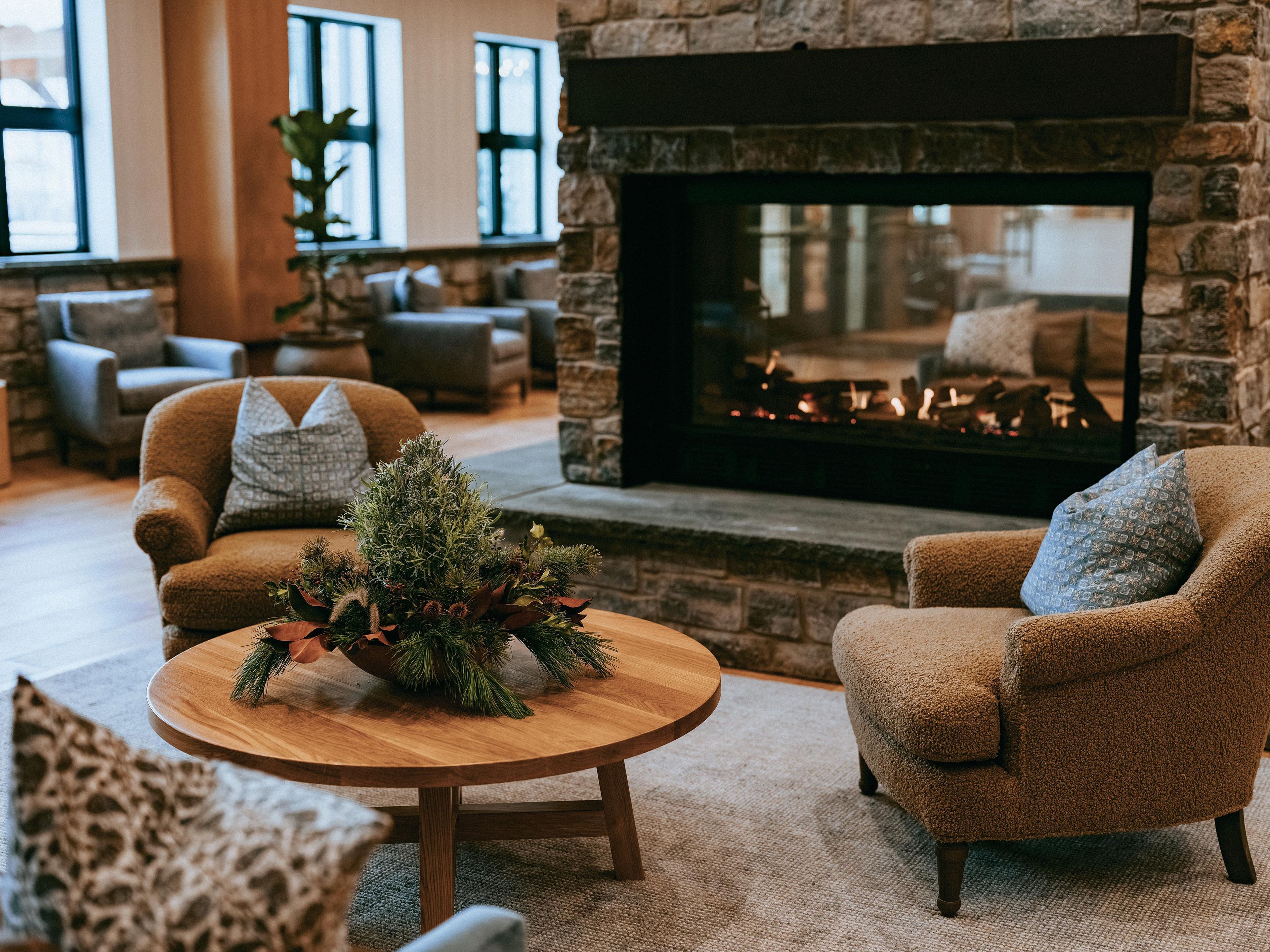 A cozy living room with a stone fireplace, comfortable seating, and a decorative centerpiece on a wooden table.