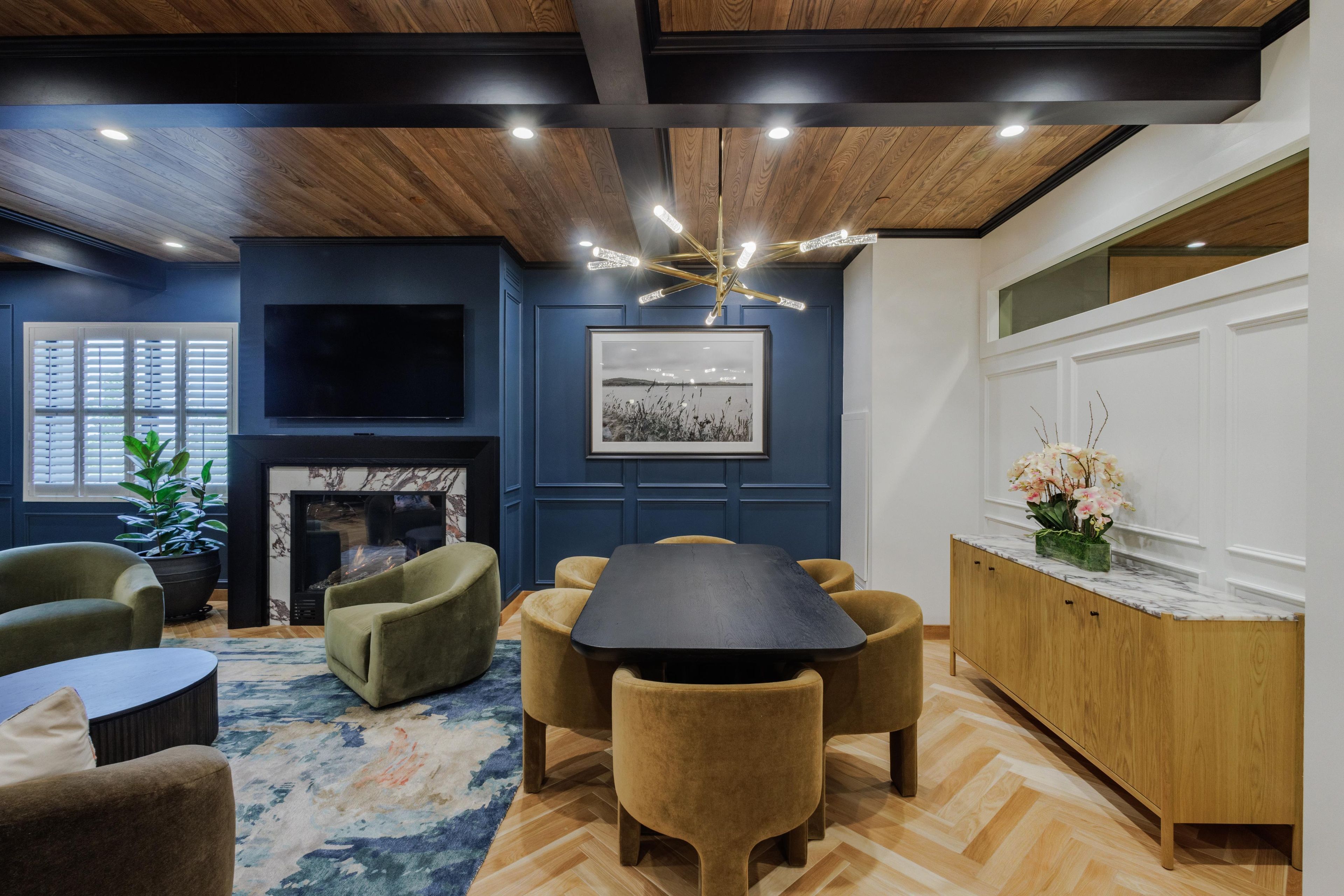 A modern living room with a fireplace, a dining area, and a kitchen with a marble countertop.