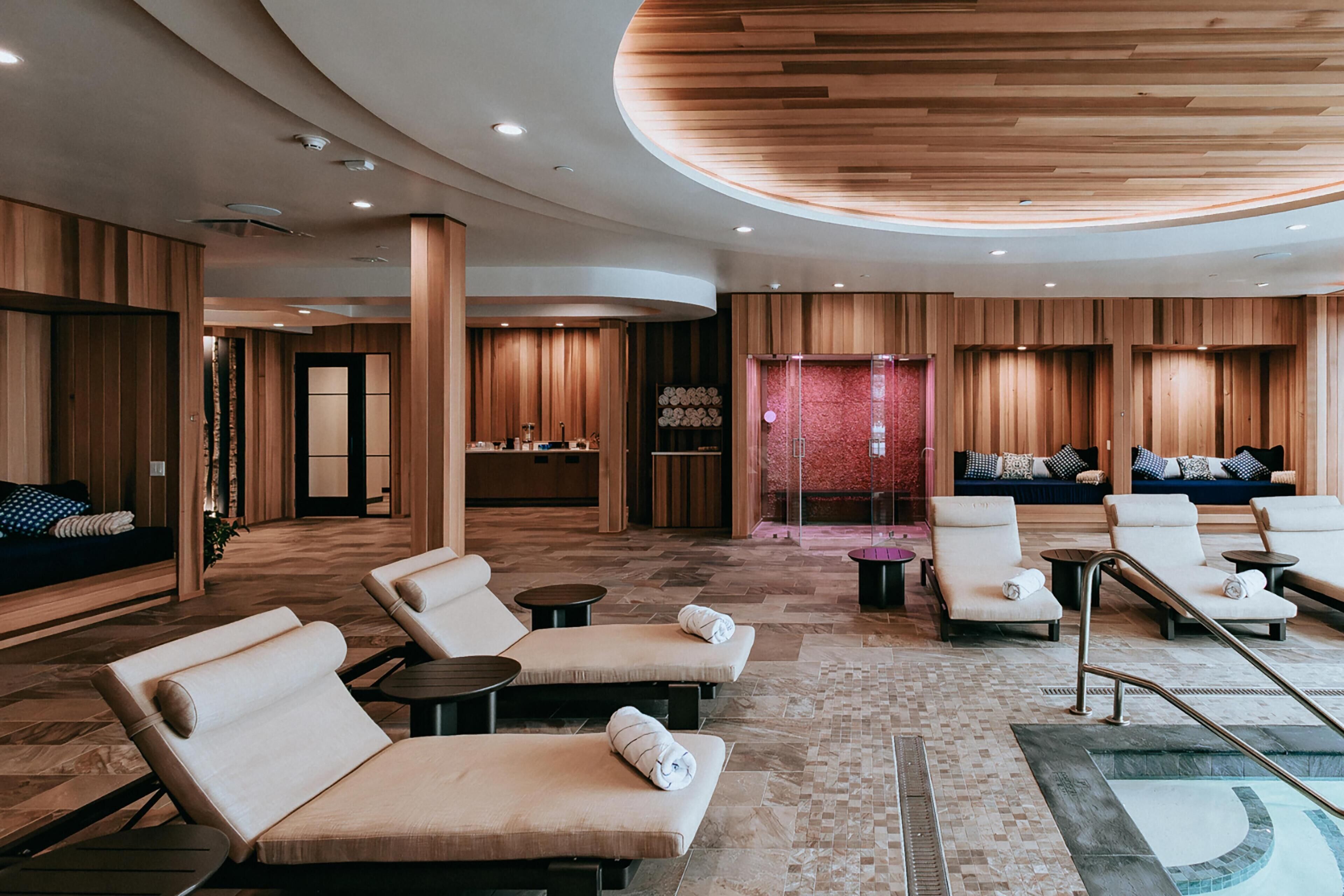 Un moderno espacio de spa con sillones reclinables, una camilla de masaje y una piscina.