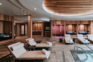 A modern spa area with lounge chairs, a massage table, and a pool. - Skaneateles Fields Resort & Spa, Curio Collection By Hilton (Skaneateles)