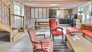 A modern living room with striped chairs, a red sofa, and a wooden coffee table.