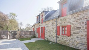 A stone building with red shutters and a paved courtyard.