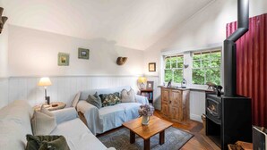 Una sala de estar acogedora con sofá, una mesa de madera, chimenea y ventana con vista a zonas verdes.