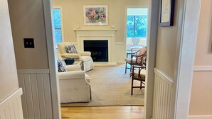 A hallway leading to a living room with a fireplace, a sofa, and a chair.